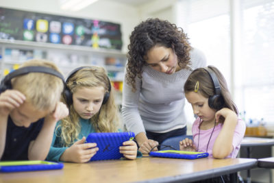 Elementary school teacher works with students on digital